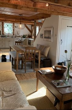 a living room filled with furniture and a wooden table in front of a kitchen area