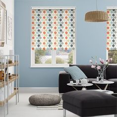 a living room with blue walls and white flooring, two windows covered in multicolored circles