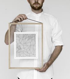 a man holding up a framed photo with lines drawn on it in front of his face