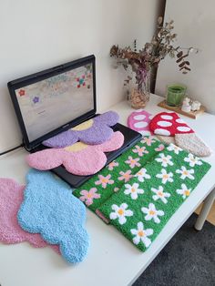 a laptop computer sitting on top of a white table covered in colorful towels and mitts