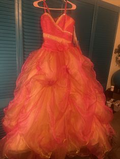 an orange and pink dress hanging on a hanger