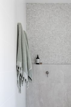 a white tiled bathroom with a towel hanging on the wall