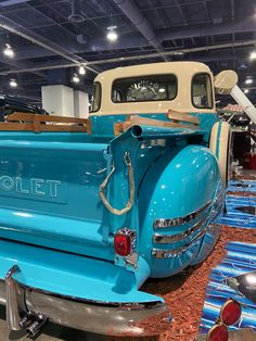 an old blue truck is on display in a showroom with other cars and trucks