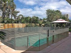 a fenced in tennis court next to a palm tree