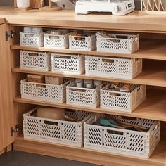 an organized kitchen cabinet with baskets and utensils