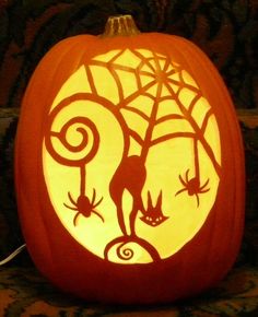 a carved pumpkin with an image of a cat and spider on it's face