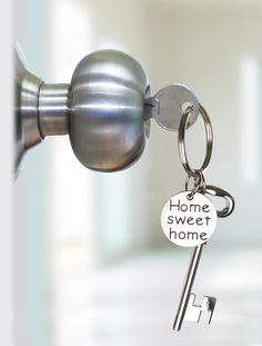 a house key hanging from a door handle with the words home sweet home written on it