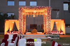 an outdoor wedding setup with white and red flowers on the stage, surrounded by chairs