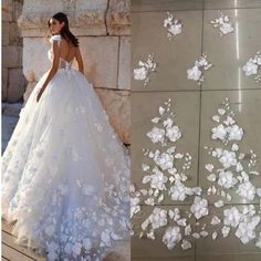 a woman in a wedding dress standing next to a wall with white flowers on it