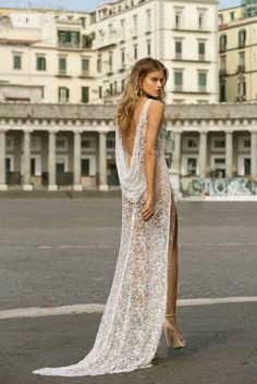 a woman in a white dress is standing on the street with her back to the camera