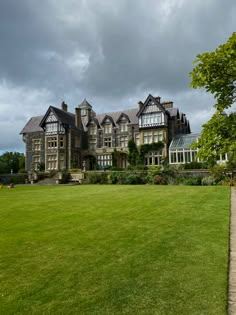 a large building with lots of windows sitting on top of a lush green field under a cloudy sky