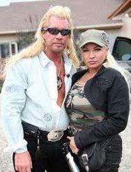 a man and woman standing next to each other in front of a house with cars