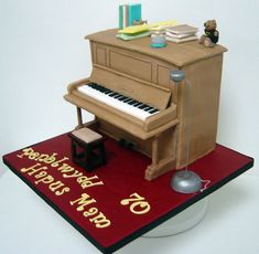 a cake that is shaped like a piano and has writing on the side, along with a teddy bear