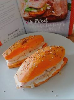 two sandwiches are on a plate next to an open book