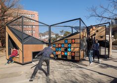 some people are playing basketball in an outdoor court with wooden structures and colorful balls on it