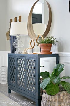 a blue cabinet with a mirror and potted plants on it in front of a white wall