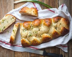 two loaves of bread sitting on top of a white towel next to a knife