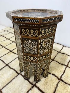 an intricately decorated table on top of a white and brown rug with black accents