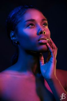 a beautiful young woman posing with her hands on her face and wearing gold jewelry, against a black background