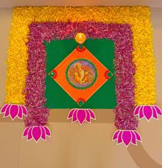 a decorated wall with flowers and an image of ganesh in the center on it