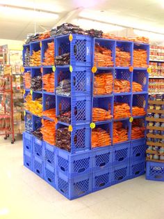 a large stack of blue crates filled with orange items in a grocery store's produce section