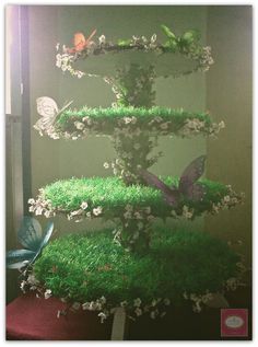 an aquarium with grass and butterflies on it's sides, in front of a window