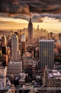 the cityscape is full of tall buildings and skyscrapers under a cloudy sky