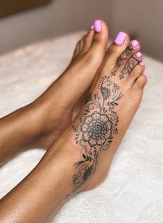 a woman's foot with a flower tattoo on her left leg and pink nail polish