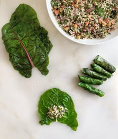 spinach and other vegetables on a white counter top next to a bowl of rice