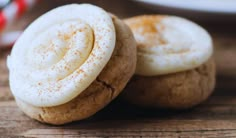 two cookies with white frosting are on a wooden table