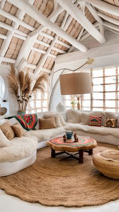 a living room filled with white furniture and lots of pillows on top of a rug