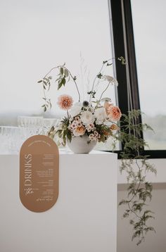 a vase filled with flowers sitting on top of a white counter next to a window