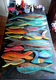 a table topped with lots of colorful fish on top of a metal counter covered in paint