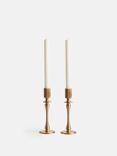 two brass candlesticks with one candle lit