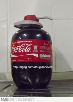 a black and red soda bottle sitting on top of a counter next to a white tile wall