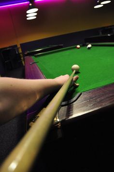 a person is playing pool in a dark room