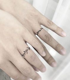 two fingers with small tattoos on them, one has an arrow and the other has a leaf