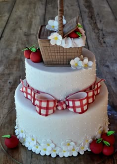 a three tiered cake with an apple on top and flowers around the edges, sitting on a wooden table