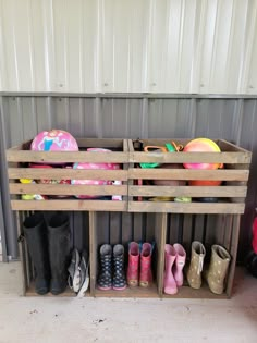 several pairs of rubber shoes are lined up in a wooden crate on the floor next to a wall