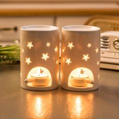 two coffee mugs sitting next to each other on a table with lights in them