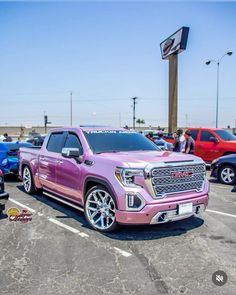 a pink truck parked in a parking lot next to other cars