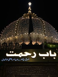 the top of a building with lights all over it at night in an arabic language