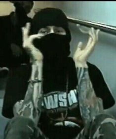 a person wearing a black hoodie and holding up their hands while sitting on a bus