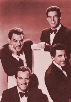 four men in tuxedos posing for a photo