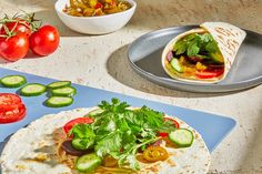 a tortilla with vegetables and sauce on the side next to a bowl of pickles