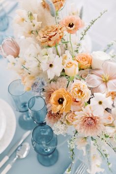 a vase filled with lots of flowers sitting on top of a blue table cloth covered table