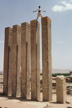 a person standing on top of two large stone pillars in the middle of a desert