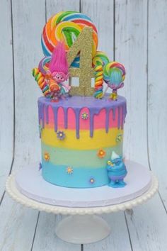 a birthday cake with the number one on it is decorated in rainbows and candies