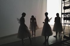 four women in tutu skirts are looking at their cell phones while standing next to each other