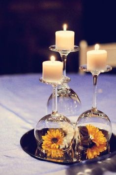 two wine glasses with sunflowers in them are sitting on a plate next to candles